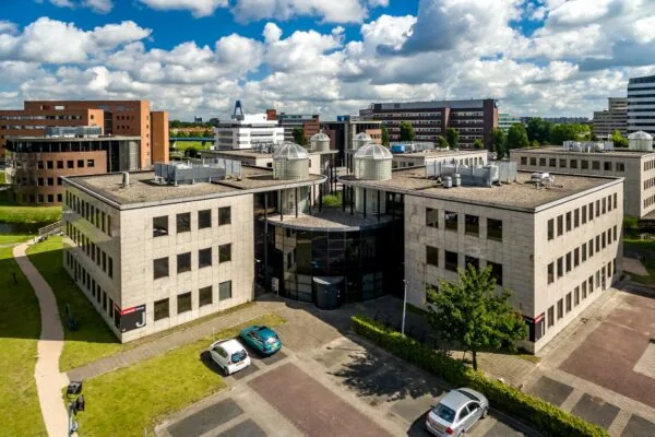 Luchtfoto van een modern kantoorgebouw aan de Rivium 1e Straat met omliggende kantoren en parkeerplaatsen.